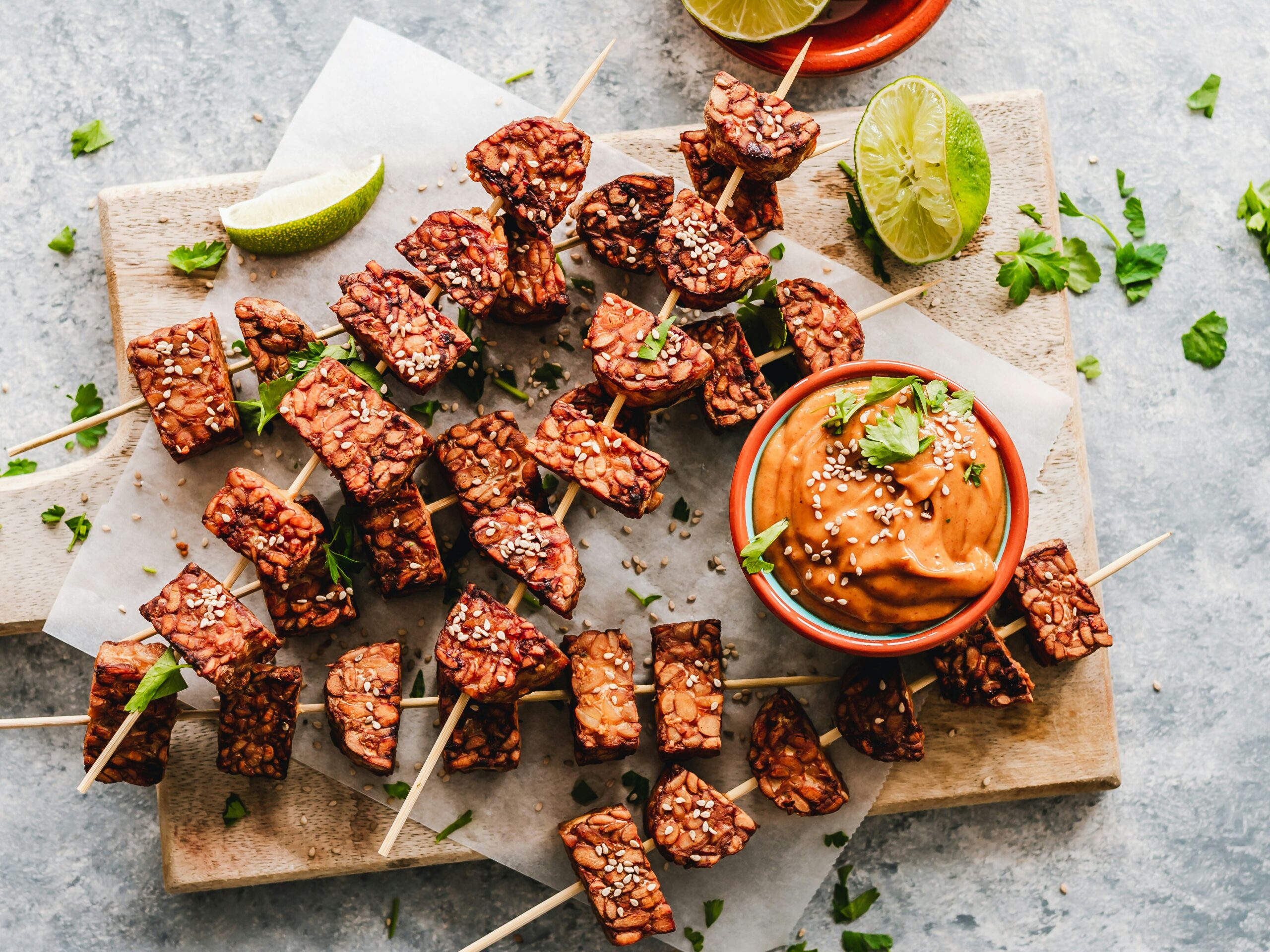 Marinated soy tempeh chunks with spicy, creamy peanut sauce and sesame seeds
