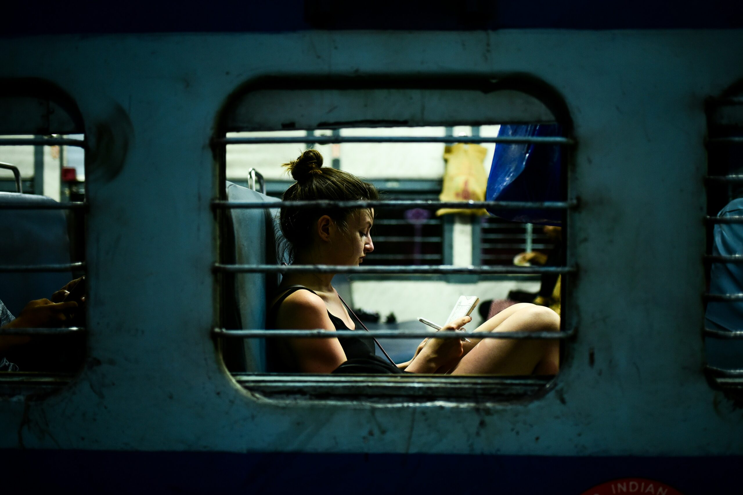 sideways view of a female traveller journalling as she sits on a train in India