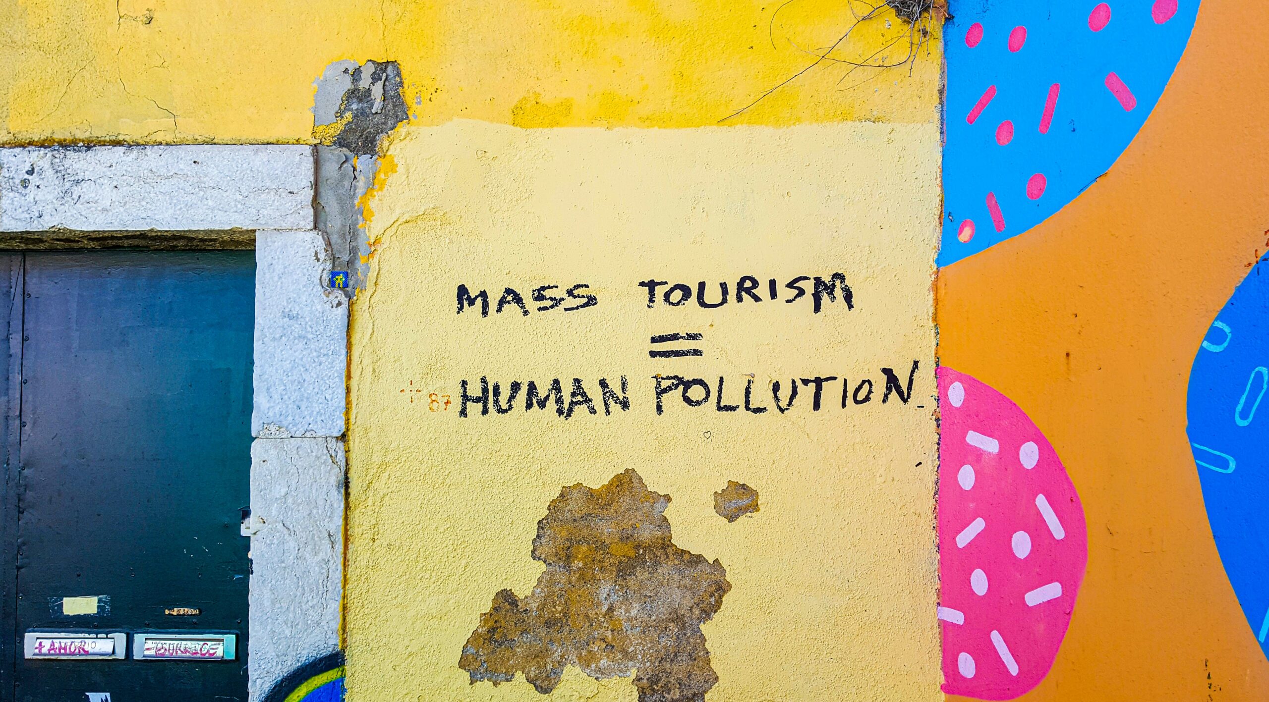 graffiti on a wall saying "Mass tourism equals human pollution"