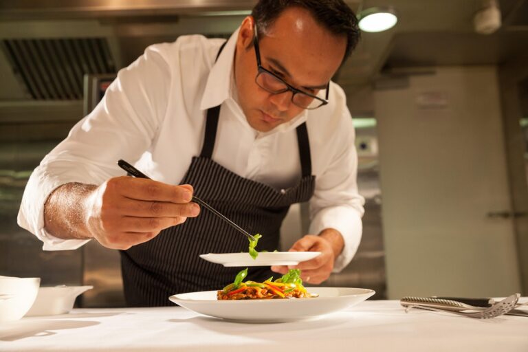 Chef carefully plating vegetables using food tweezers