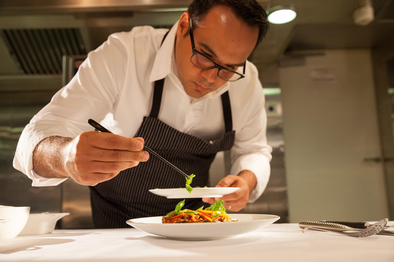 Chef carefully plating vegetables using food tweezers
